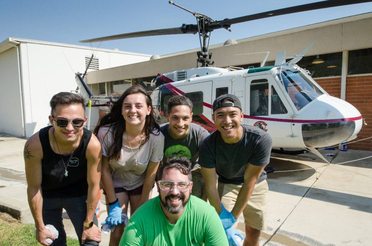 Students pose in front of the Chaffey College helicopter at the aeronautics building.
