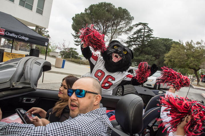 Graduate student driving a convertible and decorated car.