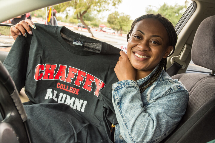 Graduate student in her car and showing a Chaffey College Alumni T-shirt