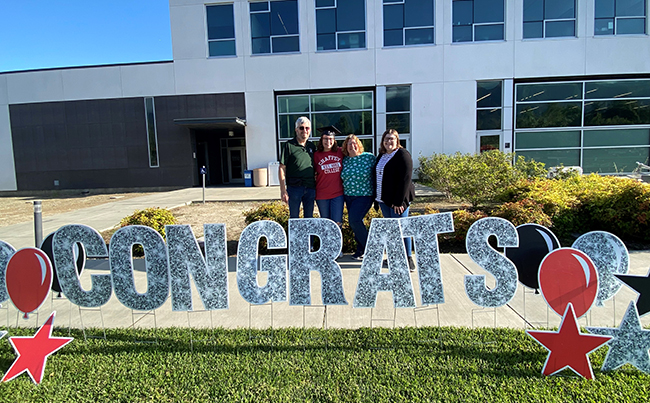 A family standing of front CAA building, celebrating the class of 2022