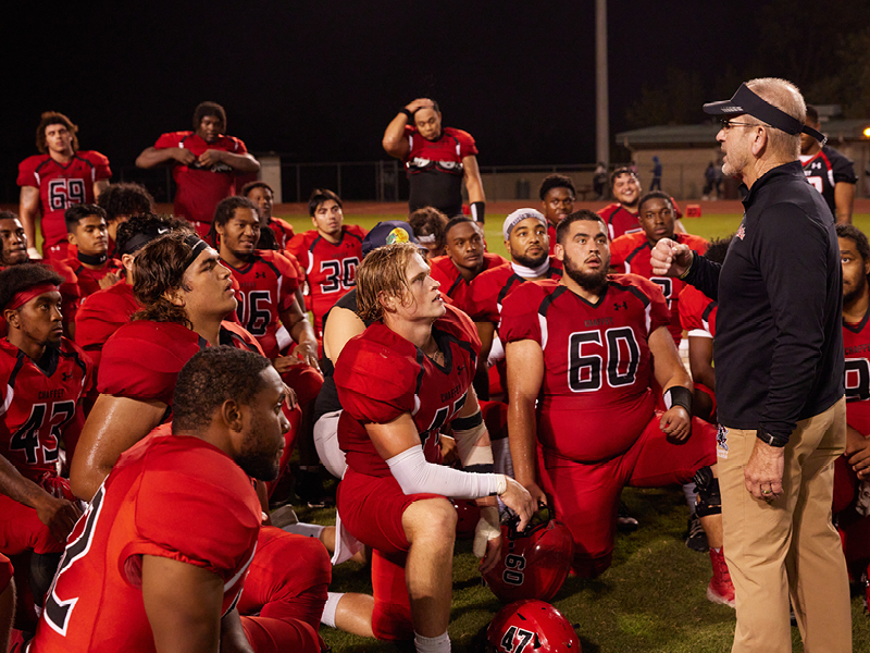 Football coach and his players on the field.