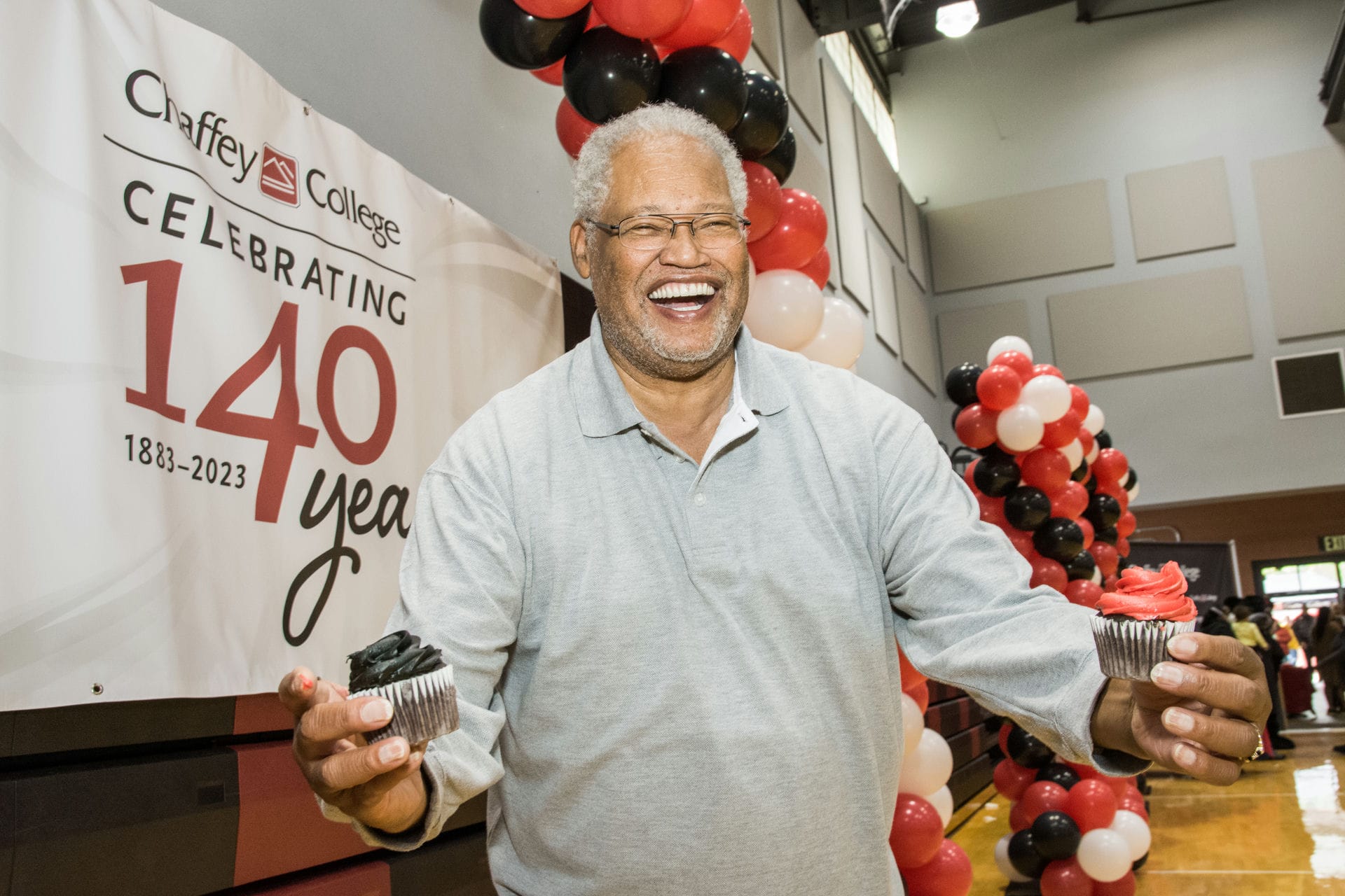 Dr. Shannon holds two cup cakes at 140 years celebration at the Rancho Cucamonga Campus