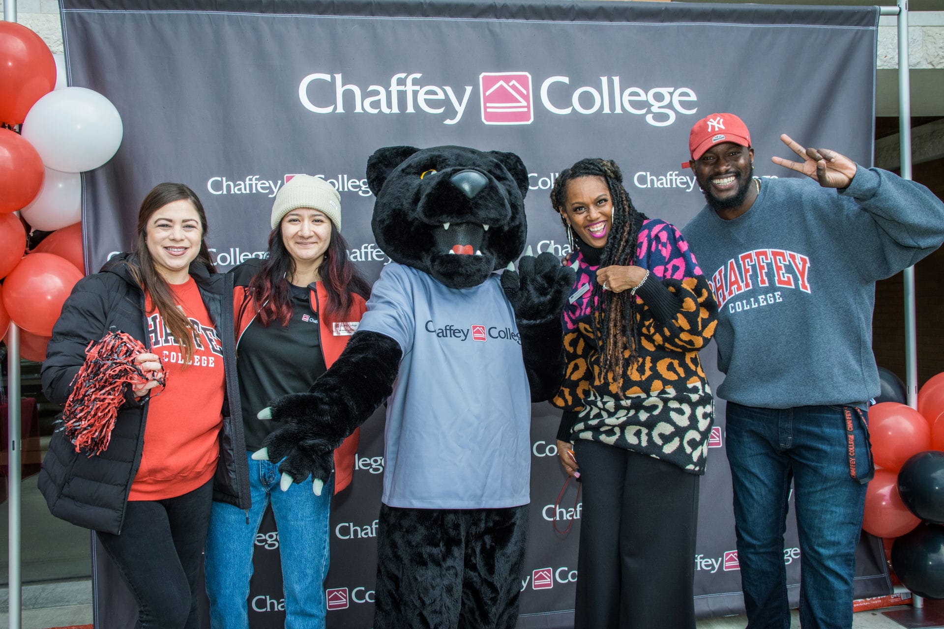 Panther mascot standing in the middle of 4 staff members.