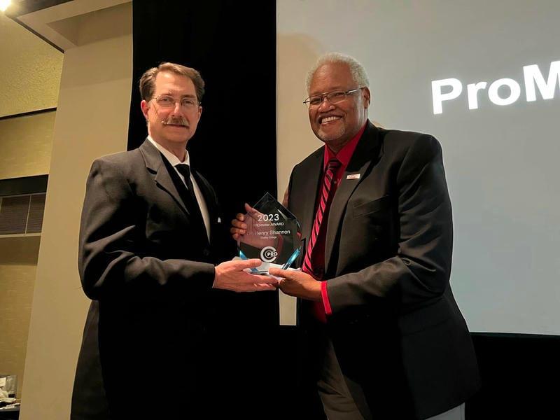 Dr. Shannon poses with Peter Griggs as he accepts the 2023 PROmoter Award from the Community College Public Relations Organization.