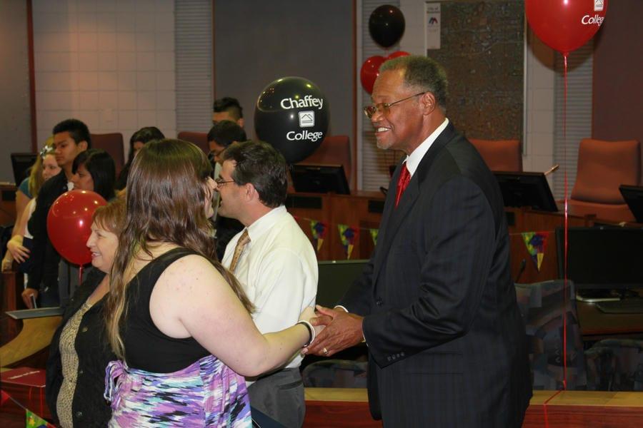 Dr. Shannon shakes an individual's hand at a graduation celebration event in 2010.