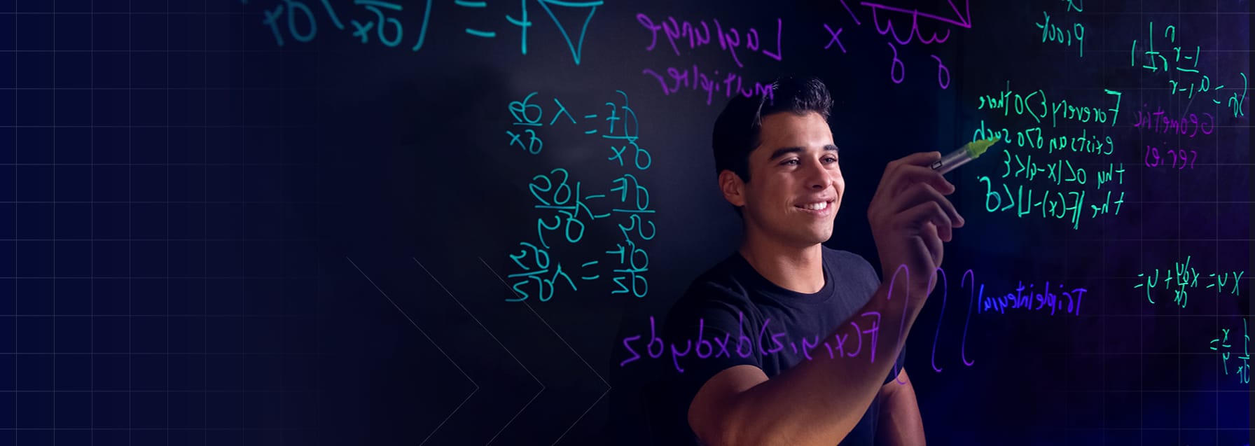 A student smiles as they work out a complex equation on a glass board. The board is covered with colorful math equations, in green, purple, and white.