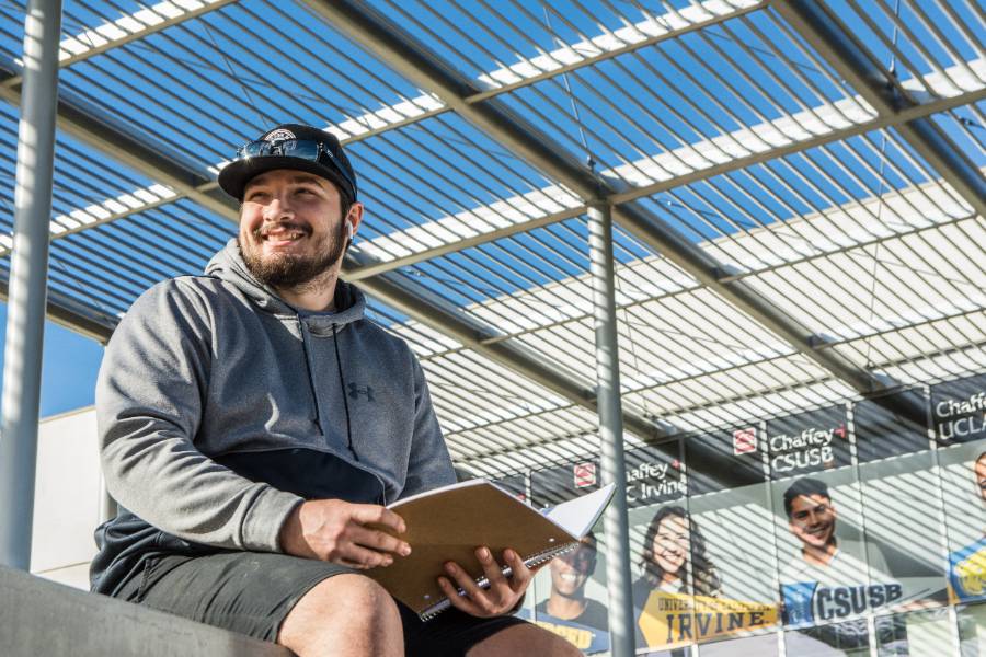 A student sits in front of the Student Services and Administration building