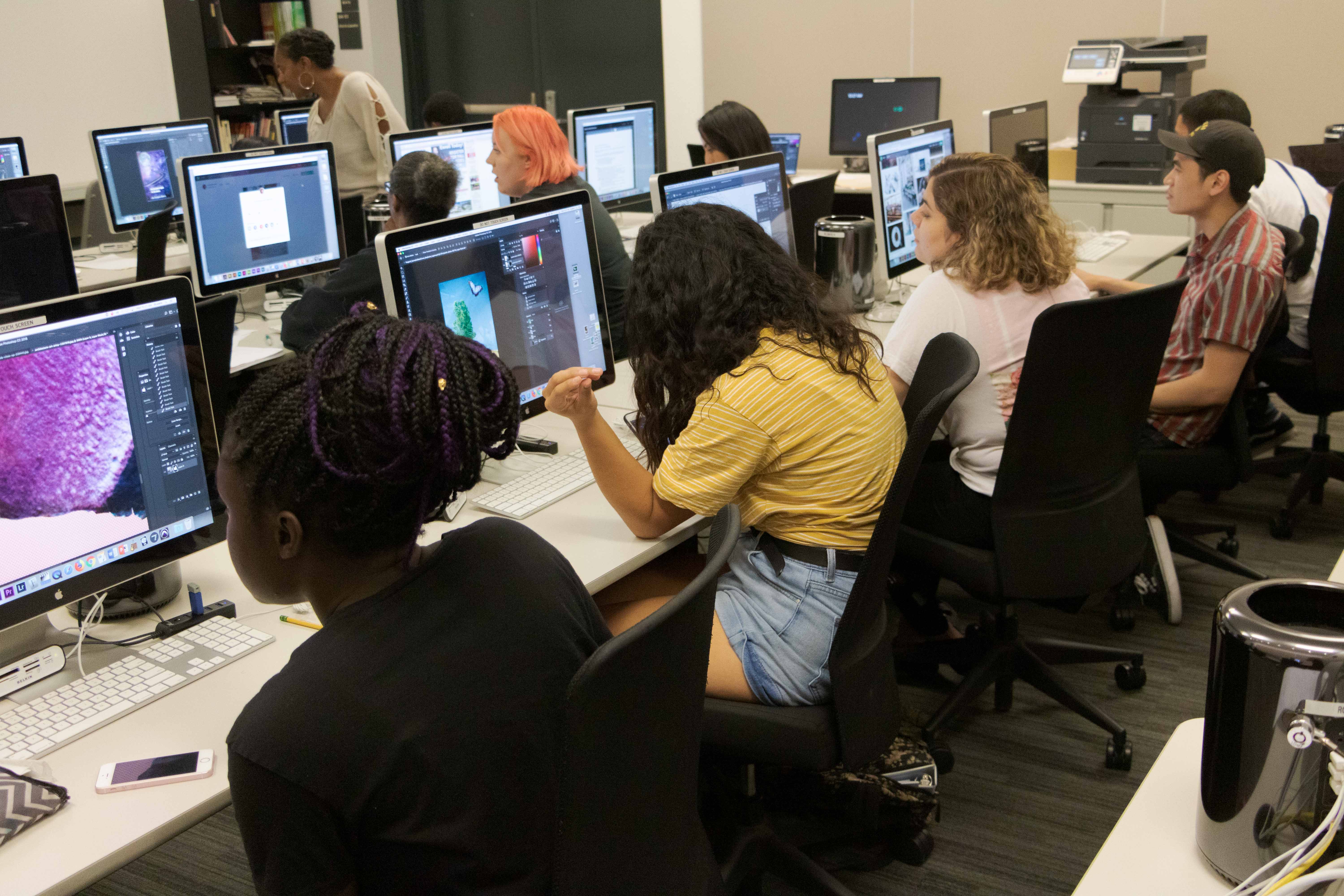 Students in a graphic design class sit at computers.