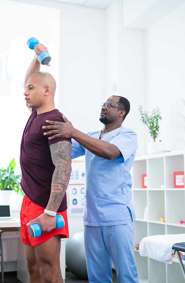 Therapist in glasses and blue uniform assisting bodybuilder after injury