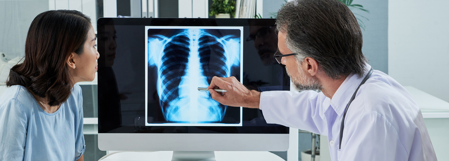 Doctor explaining lungs x-ray on computer screen to young patient