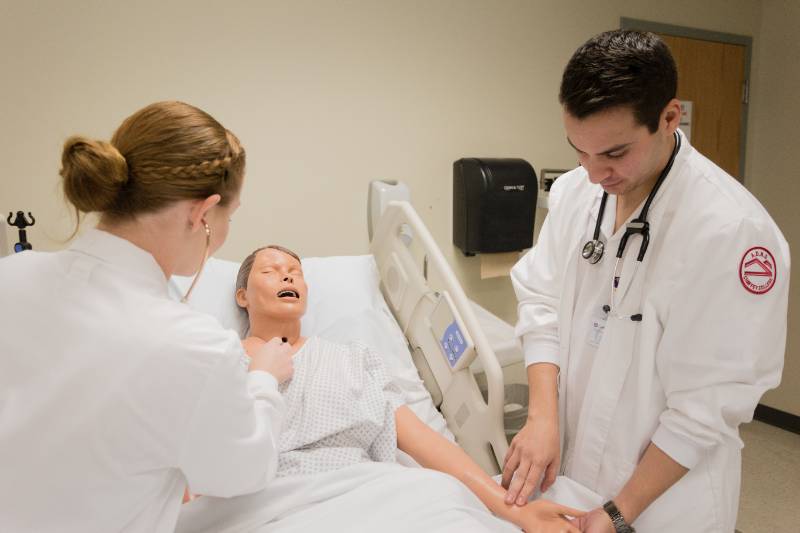 Nursing students work in a lab environment.