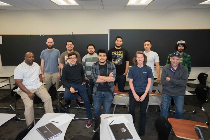 A group of engineering students pose in a classroom.