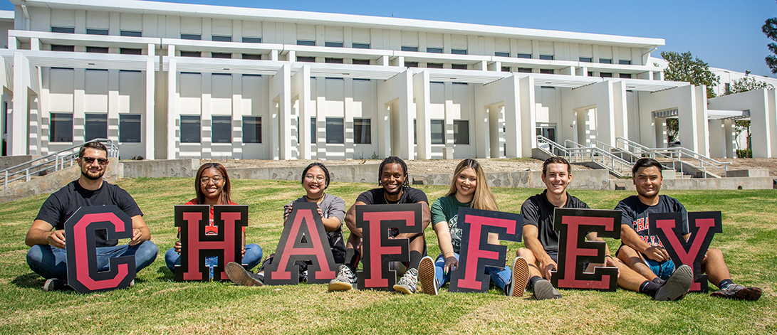 students holding chaffey letters by library