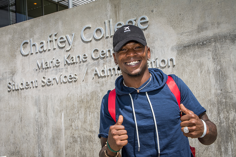 A Chaffey College student stands in front of the student services/administration building.