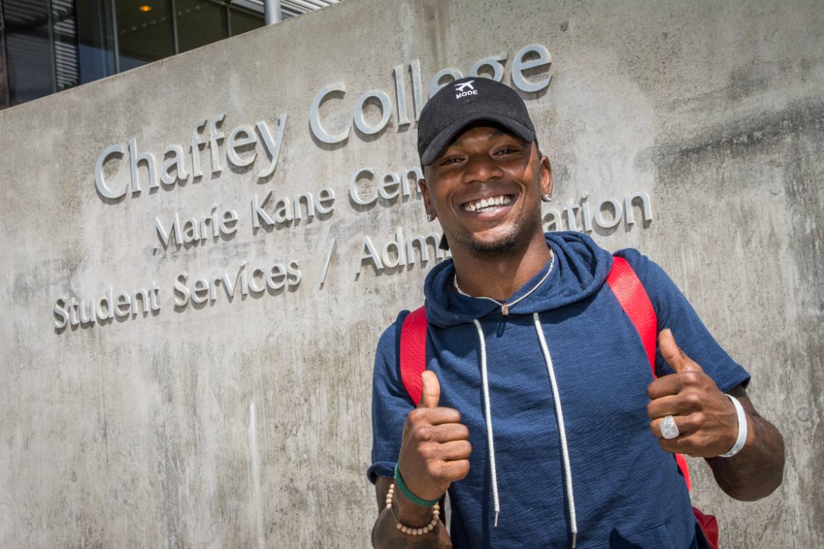 A male African American student standing in front of the Administration building