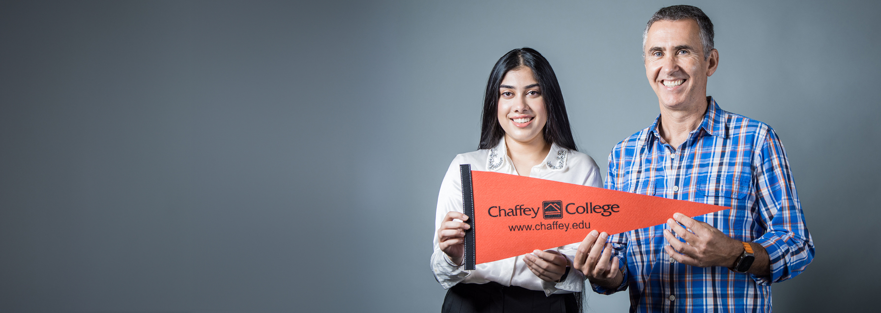 faculty and student image holding a Chaffey pennant