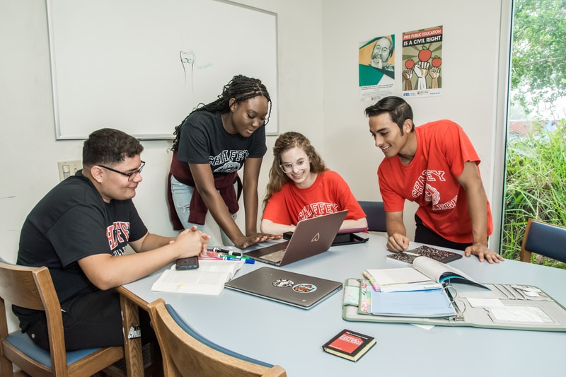 Student smiling and studying together while looking at a laptop