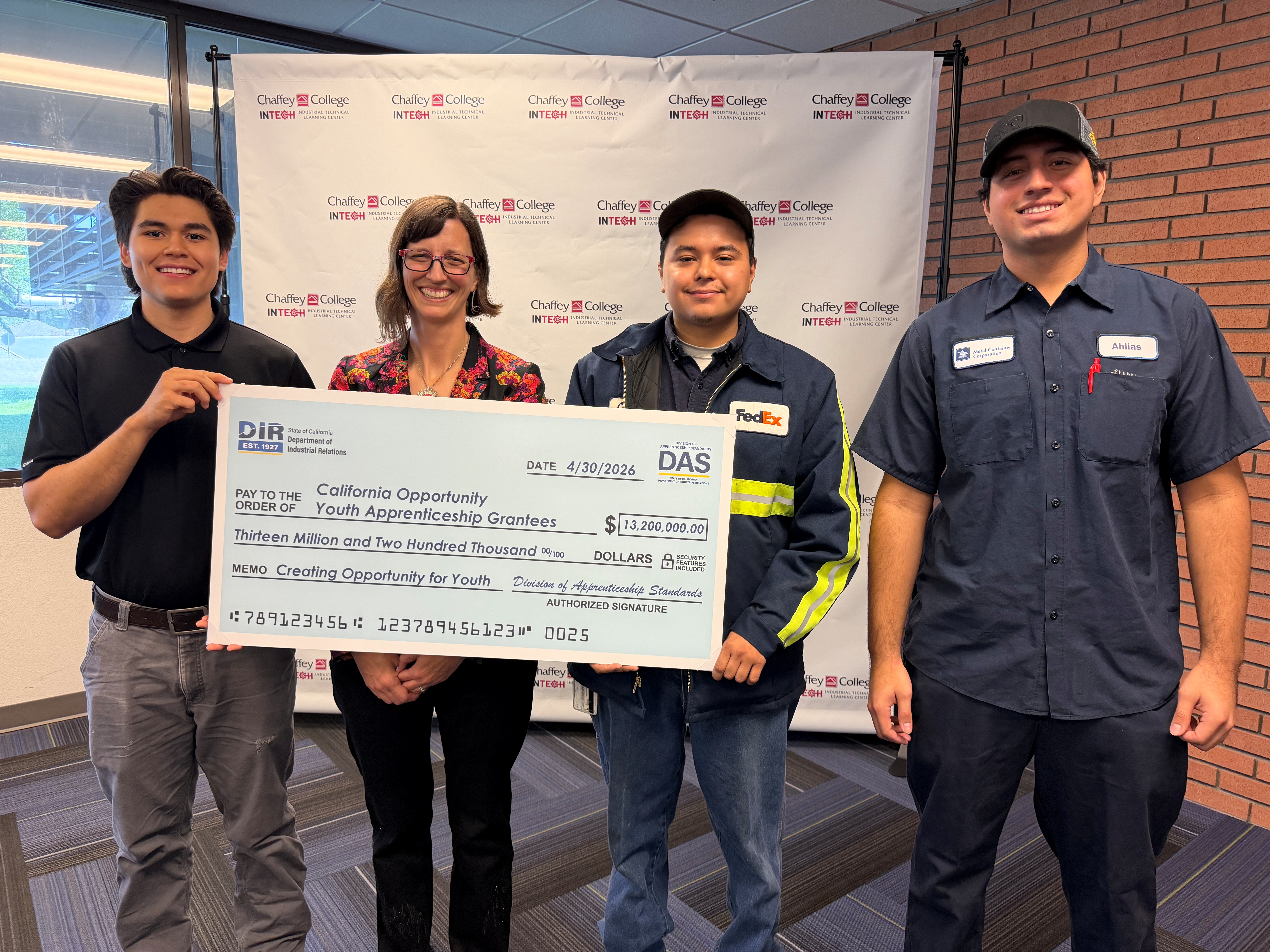 COYA students and the chief of the Division of Apprenticeship Standards hold a symbolic check for $13.2 million.