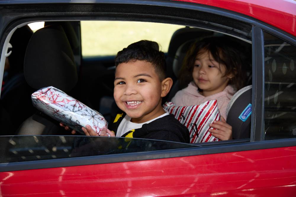 A child holds a wrapped gift and smiles.