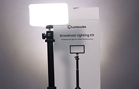A bright LED panel from the Lume Cube Broadcast Lighting Kit is mounted on a black adjustable stand, with its packaging box visible in the background.
