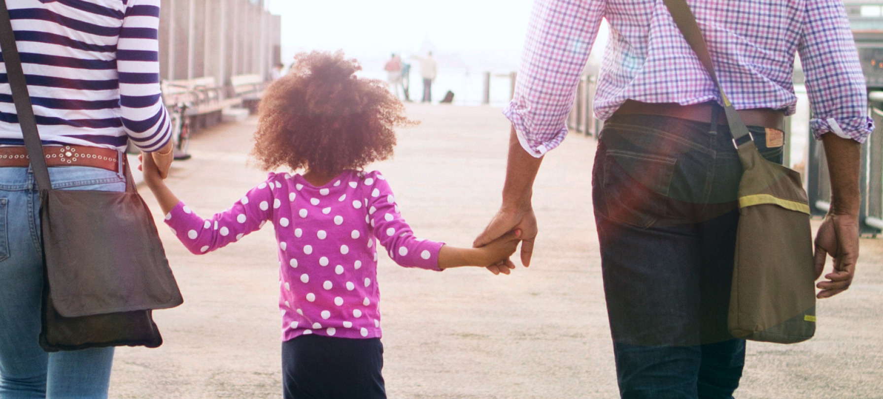 parents walking and holding a child's hands