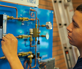 Industrial Electrical and Mechanical student adjusting settings on circuit board